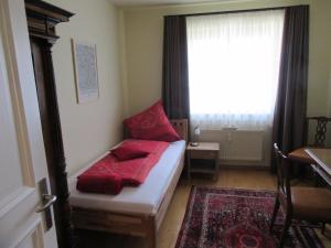 a small bedroom with a bed with red pillows on it at Ferienwohnung Alpenvilla in Bischofswiesen