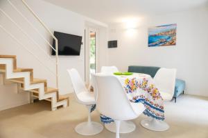 a white dining room with a table and white chairs at Cefalù Beach Garden House in Cefalù