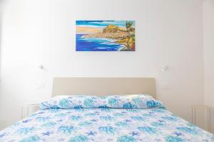 a bedroom with a bed with a painting on the wall at Cefalù Beach Garden House in Cefalù