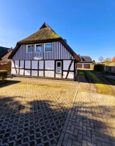 a large house with a roof on a brick road at Haegerende _Alte Liebe_ in Groß Kirr