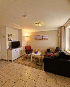 a living room with a black couch and a tv at Haegerende _Seitensprung_ in Groß Kirr