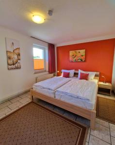 a bedroom with a large bed with an orange wall at Haegerende _Seitensprung_ in Groß Kirr