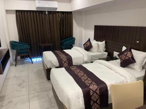 a hotel room with two beds and a television at Hotel Mahavir in Ankleshwar