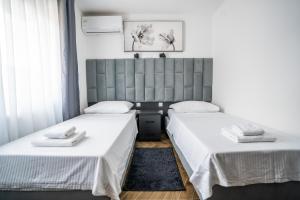 two beds in a room with white sheets at Sobe Biser Dunava - smještaj uz Dunav in Vukovar