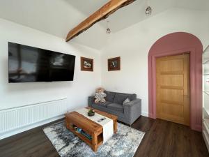 a living room with a couch and a tv on the wall at Rushbrooke cottages in Edenderry