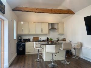 a kitchen with white cabinets and a counter with chairs at Rushbrooke cottages in Edenderry