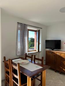 a dining room with a table and a television at Casetta al Belvedere - Lake View in Vercana