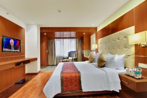 a hotel room with a large bed and a television at Lavender Premier in Bangalore