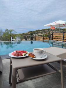 a table with a plate of fruit and a cup of coffee at Saranda's Crown in Sarandë