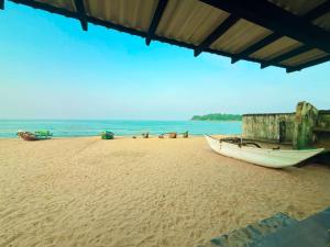a boat sitting on a sandy beach next to the ocean at Trinco Beach Bunks in Trincomalee