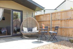 a patio with a swing and a table and chairs at Pear Tree Cabin in Whitstable +9 photos