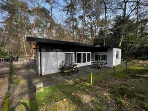 a small white cabin with a black roof in the woods at Bonte Specht in Otterlo
