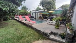 a backyard with a pool with chairs and an umbrella at La Kaz Zarlor in Saint-Paul