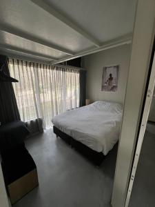 a bedroom with a bed and a large window at Bonte Specht in Otterlo