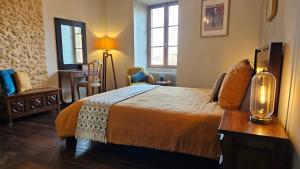 a bedroom with a bed and a table with a lamp at Planches et Plonk in Belvès