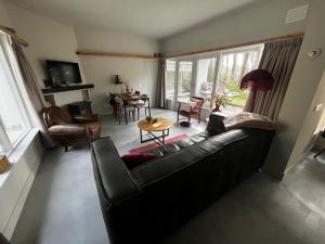a living room with a black couch and a table at Bonte Specht in Otterlo