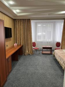 a hotel room with a bed and a desk at Aq-Jaiyq Halal Hotel in Karagandy