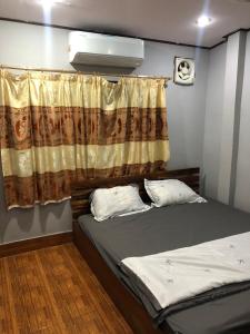 a bedroom with a bed and a curtain and a window at Fundee Guesthouse in Pakse