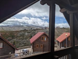 a view of a mountain from a house window at Chalé 24 in Penhas da Saúde