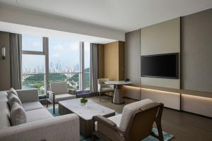 a living room with a tv and a couch and chairs at Changsha Marriott Hotel West in Changsha