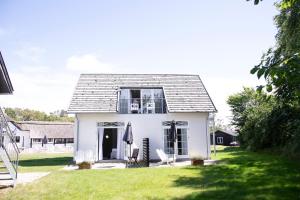 a white house with two chairs and an umbrella at Hotel Strandgaarden in Vesterø Havn