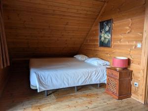 a bed in a wooden cabin with a night stand at Chalé 24 in Penhas da Saúde