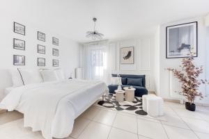 a white bedroom with a white bed and a blue chair at L'Écrin Piano, chic near Paris in Asnières-sur-Seine