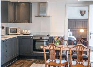 a kitchen with dark cabinets and a table and chairs at The Ollerod in Beaminster