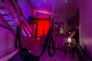 a purple room with a bed and a swing at love escape "Love Room" in Saint-Paul-Trois-Châteaux