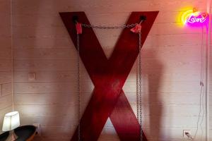 a red mirror hanging on a wall with a chain at love escape "Love Room" in Saint-Paul-Trois-Châteaux