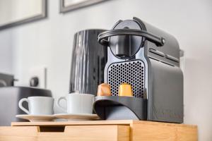 a coffee maker sitting on a counter with cups at L'Écrin Piano, chic near Paris in Asnières-sur-Seine