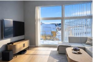 a living room with a television and a large window at Nordic Comfort Suite with Hot Tub in Storeidet