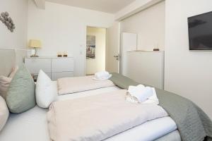a white room with two beds and a tv at Ostsee Suite 1 - Strandperle in Niendorf