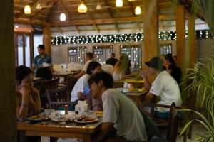 a group of people sitting at tables in a restaurant at Shallow Lagoon Sunset in Rasdhoo