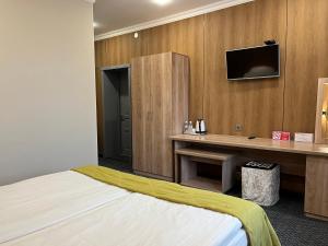 a hotel room with a bed and a desk and a tv at Aq-Jaiyq Halal Hotel in Karagandy +41 photos