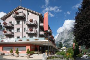 a large pink building with a mountain in the background at Parkhotel Schoenegg in Grindelwald +58 photos