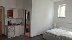 a bedroom with a bed and a kitchen with a mirror at Penzion TGM in Příbram