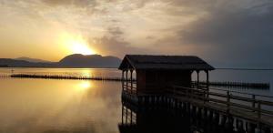 a wooden dock in the water with the sunset in the background at Messolonghi Holy City in Missolonghi