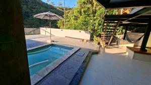 a swimming pool with an umbrella next to a house at Loft com piscina, sauna e hidro in Niterói