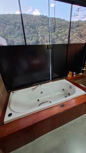 a bath tub in a room with a large window at Loft com piscina, sauna e hidro in Niterói +12 photos