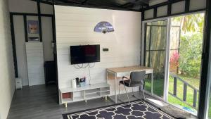 a room with a desk and a tv on a wall at Secret Garden House - 2BR Cozy Home with Garden & Workspace in Ban Tai