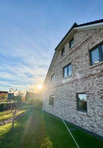 a brick building with the sun setting behind it at Vollmöblierte hochwertige neue Apartments in Klevendeich