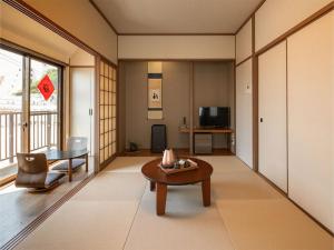 a living room with a table and a tv at Shirahama no Yado Daigo in Shirahama