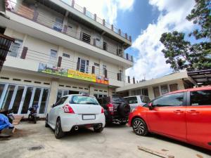 two cars parked in a parking lot in front of a building at Dago Hotel Salon FORA in Bandung