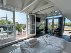 a bedroom with a bed and a balcony with windows at Hotel Strandgaarden in Vesterø Havn