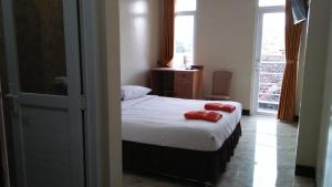 a bedroom with a bed with two red pillows on it at Dago Hotel Salon FORA in Bandung +7 photos