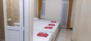 two beds in a room with two red bags on them at Dago Hotel Salon FORA in Bandung