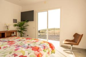 a bedroom with a bed and a chair and a window at Finca el Vinche in Guía de Isora