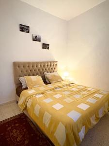 a bedroom with a large bed with a yellow and white comforter at Appartement Ettahrir in Tunis