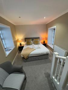 a bedroom with a bed and a couch and two windows at The Covenanter Hotel in Falkland